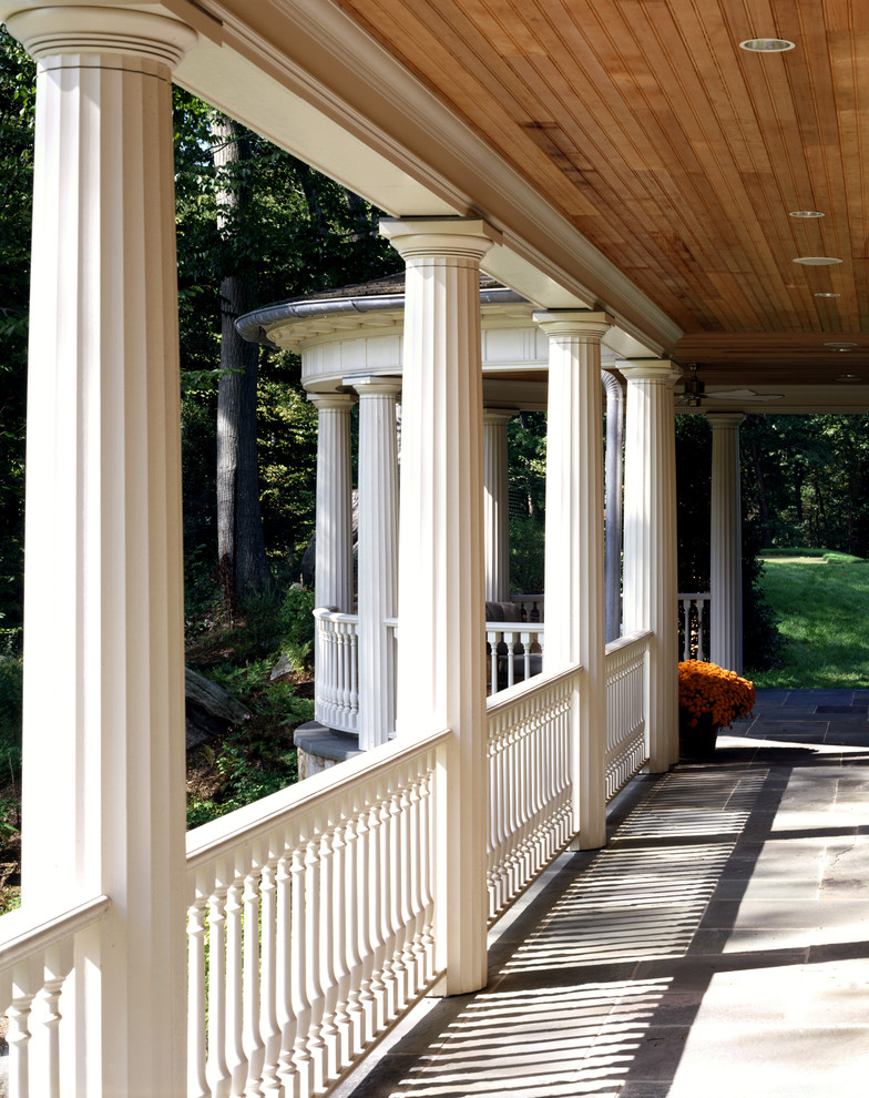 Photo of an expansive traditional backyard verandah in New York with natural stone pavers and a roof extension.