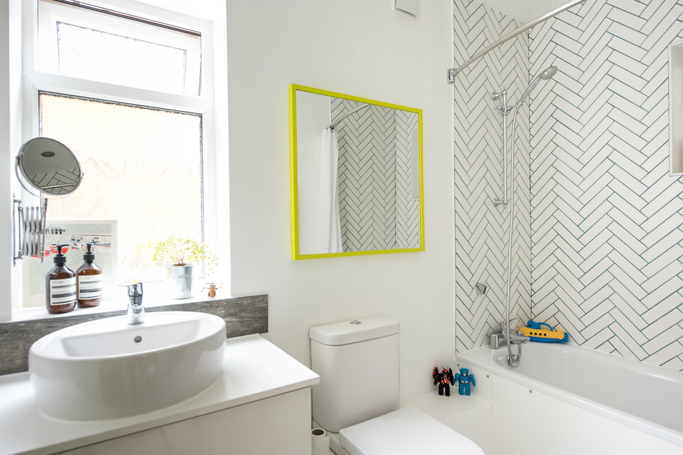 Small eclectic kids bathroom in London with white cabinets, a shower/bathtub combo, white tile, ceramic tile, white walls, a drop-in tub, a vessel sink, a two-piece toilet and white benchtops.