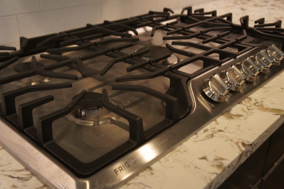Example of a transitional u-shaped eat-in kitchen design with a farmhouse sink, flat-panel cabinets, white backsplash, ceramic backsplash, stainless steel appliances and an island