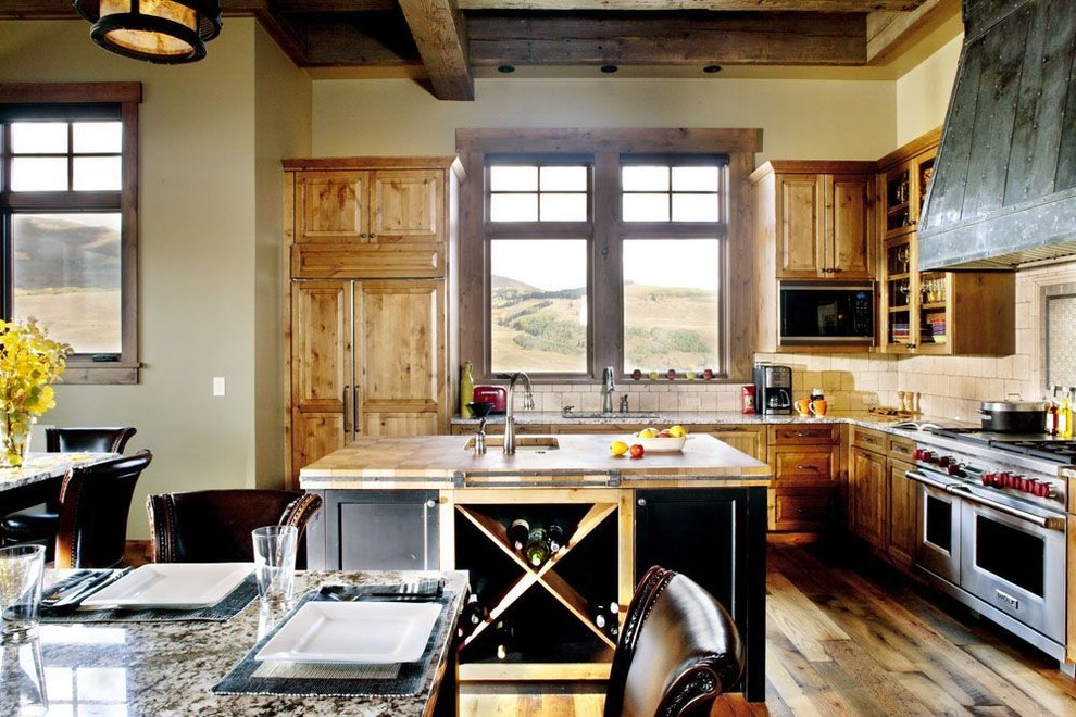 Large mountain style l-shaped medium tone wood floor open concept kitchen photo in Denver with a single-bowl sink, raised-panel cabinets, medium tone wood cabinets, granite countertops, beige backsplash, stone tile backsplash, stainless steel appliances and two islands