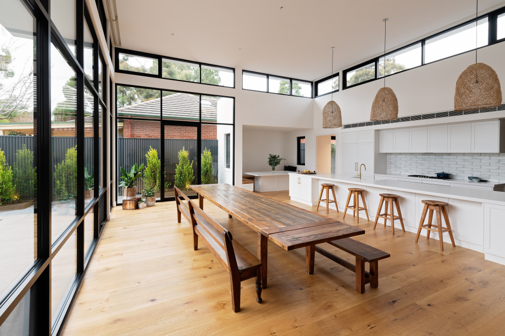 Inspiration pour une salle à manger ouverte sur la cuisine traditionnelle de taille moyenne avec un mur blanc, un sol en bois brun, aucune cheminée et un sol marron.