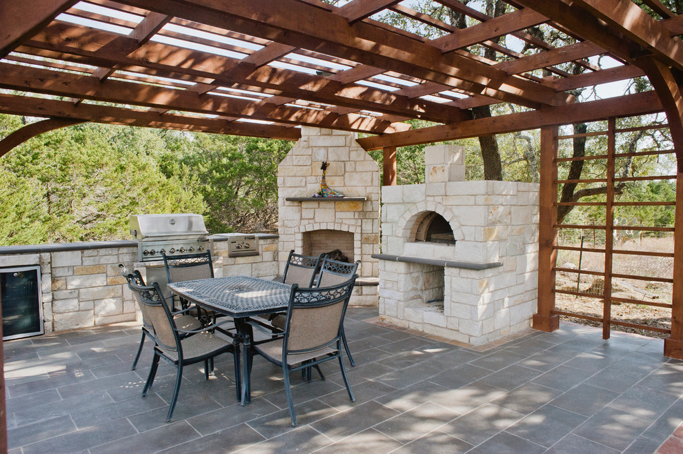 This is an example of an expansive backyard patio in Austin with tile, an outdoor kitchen and a pergola.