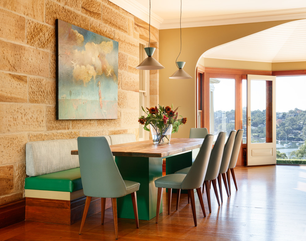 This is an example of a transitional dining room in Sydney with yellow walls, medium hardwood floors and brown floor.