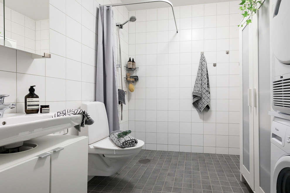 Scandinavian 3/4 bathroom in Stockholm with flat-panel cabinets, white cabinets, a curbless shower, white tile, white walls, a wall-mount sink, grey floor and a shower curtain.