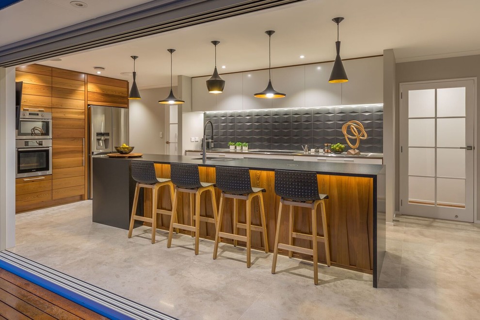 Modern kitchen in Auckland with black splashback, ceramic splashback, stainless steel appliances and limestone floors.