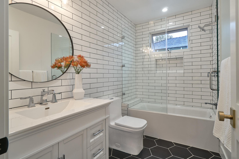 This is an example of a mid-sized modern bathroom in Los Angeles with shaker cabinets, white cabinets, an undermount tub, a shower/bathtub combo, a one-piece toilet, multi-coloured tile, ceramic tile, porcelain floors, solid surface benchtops, black floor, white benchtops and a single vanity.