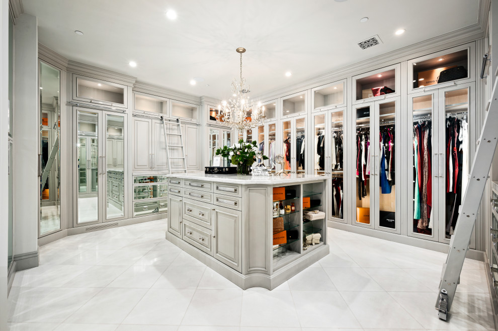 На фото: огромная гардеробная комната унисекс в стиле ретро с стеклянными фасадами, светлыми деревянными фасадами, мраморным полом и белым полом