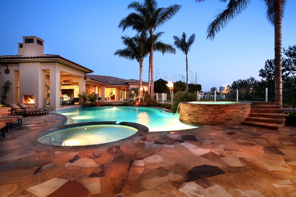 Large mediterranean backyard custom-shaped lap pool in Orange County with a pool house and natural stone pavers.