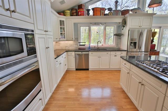 Inspiration for a large eclectic l-shaped light wood floor open concept kitchen remodel with a double-bowl sink, raised-panel cabinets, white cabinets, marble countertops, stainless steel appliances and an island