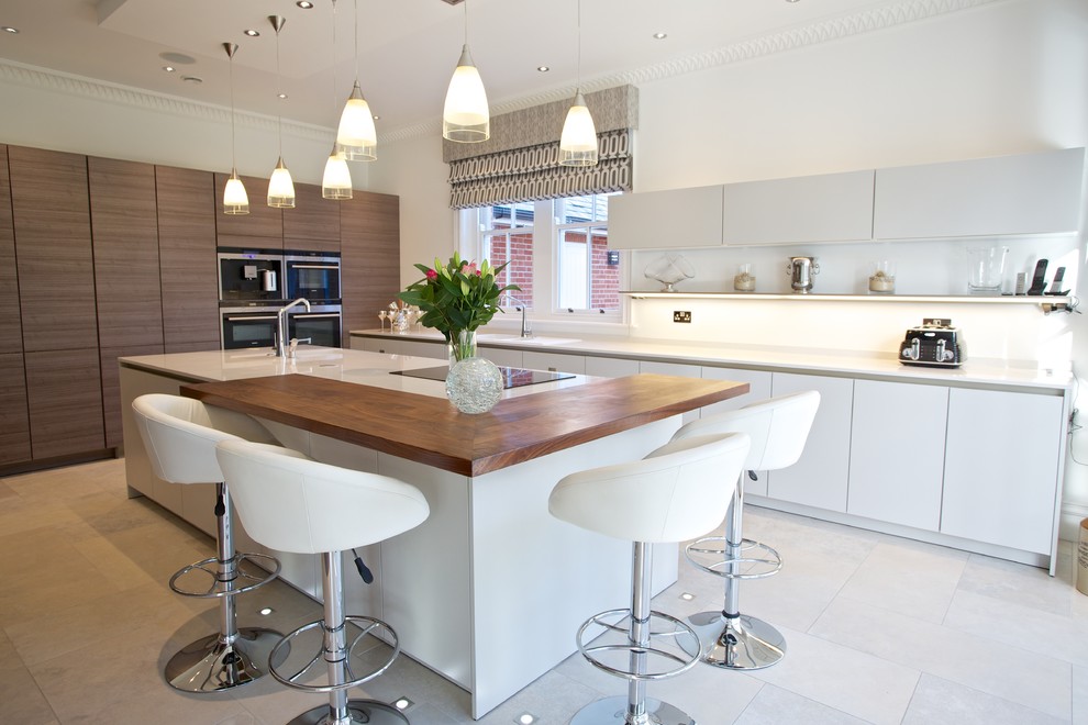 Inspiration for a contemporary galley kitchen in Hampshire with flat-panel cabinets, white cabinets, with island and stainless steel appliances.