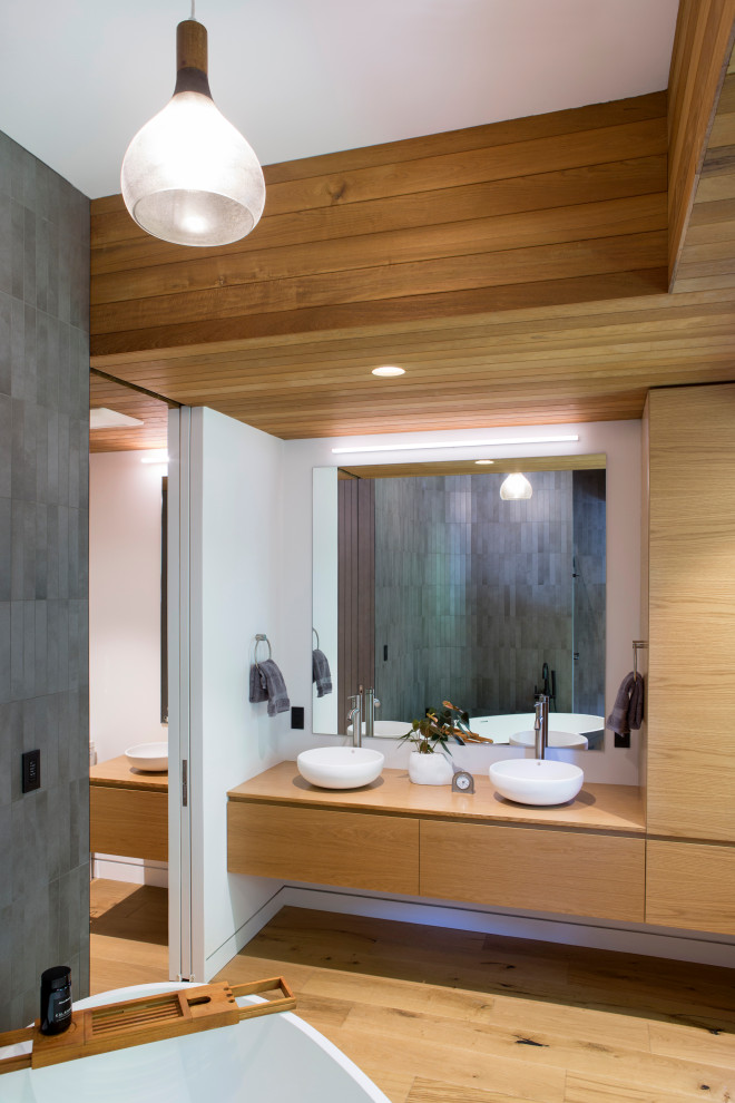 Bathroom - small modern master gray tile and ceramic tile light wood floor, beige floor, double-sink and tray ceiling bathroom idea in New York with flat-panel cabinets, beige cabinets, white walls, a vessel sink, wood countertops, a hinged shower door, beige countertops and a floating vanity