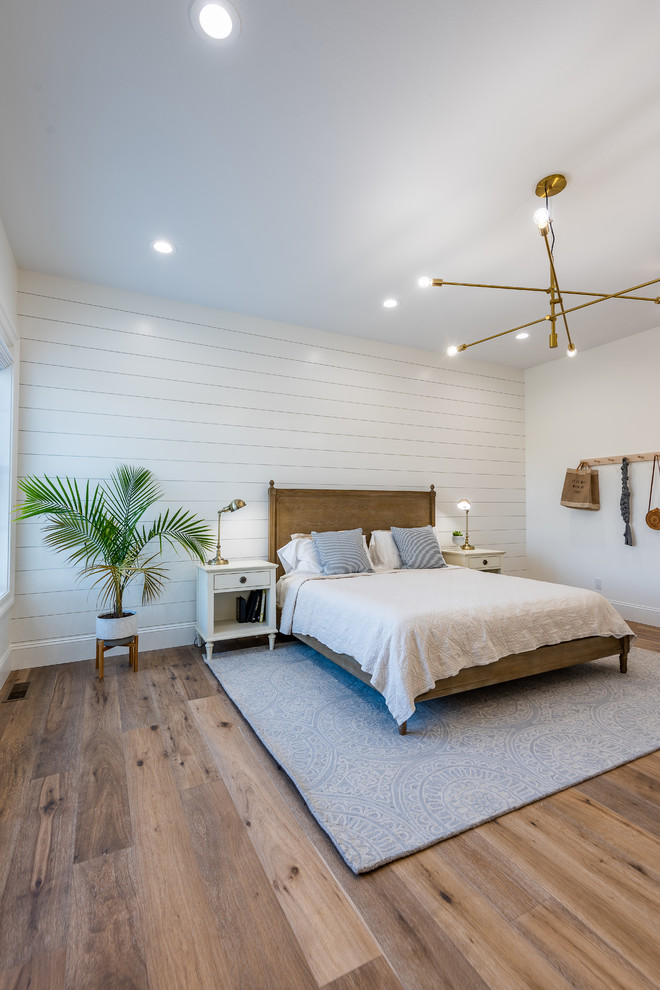 Country guest bedroom in Other with white walls, medium hardwood floors and brown floor.