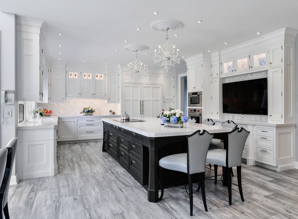 This is an example of a large transitional u-shaped eat-in kitchen in New York with an integrated sink, recessed-panel cabinets, white cabinets, quartz benchtops, white splashback, marble splashback, panelled appliances, porcelain floors, with island, grey floor and white benchtop.