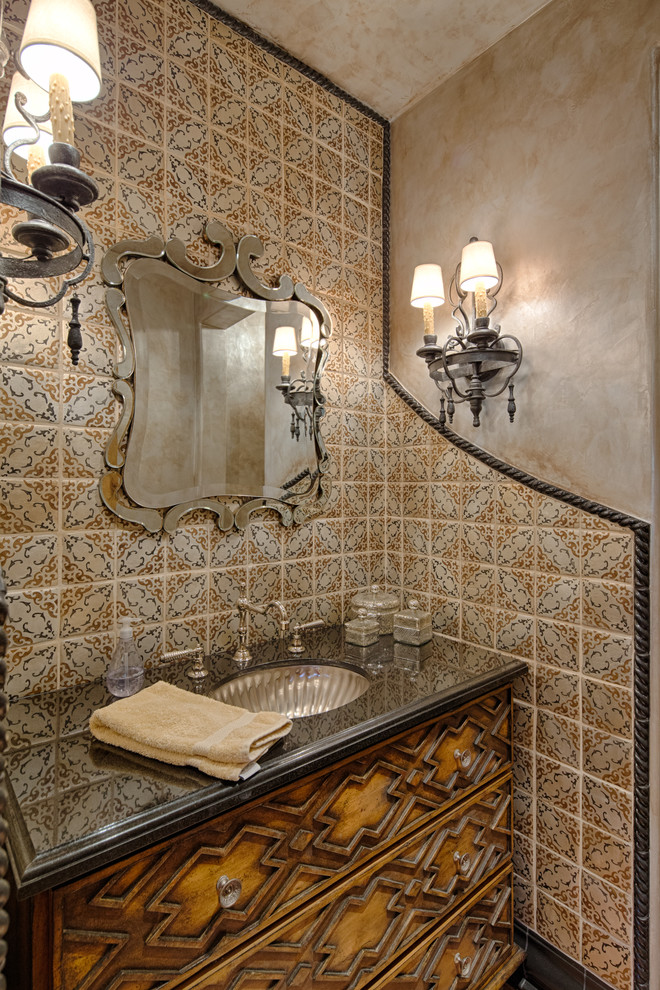 This is an example of a mediterranean powder room in Phoenix with an undermount sink, furniture-like cabinets, medium wood cabinets, multi-coloured tile and beige walls.