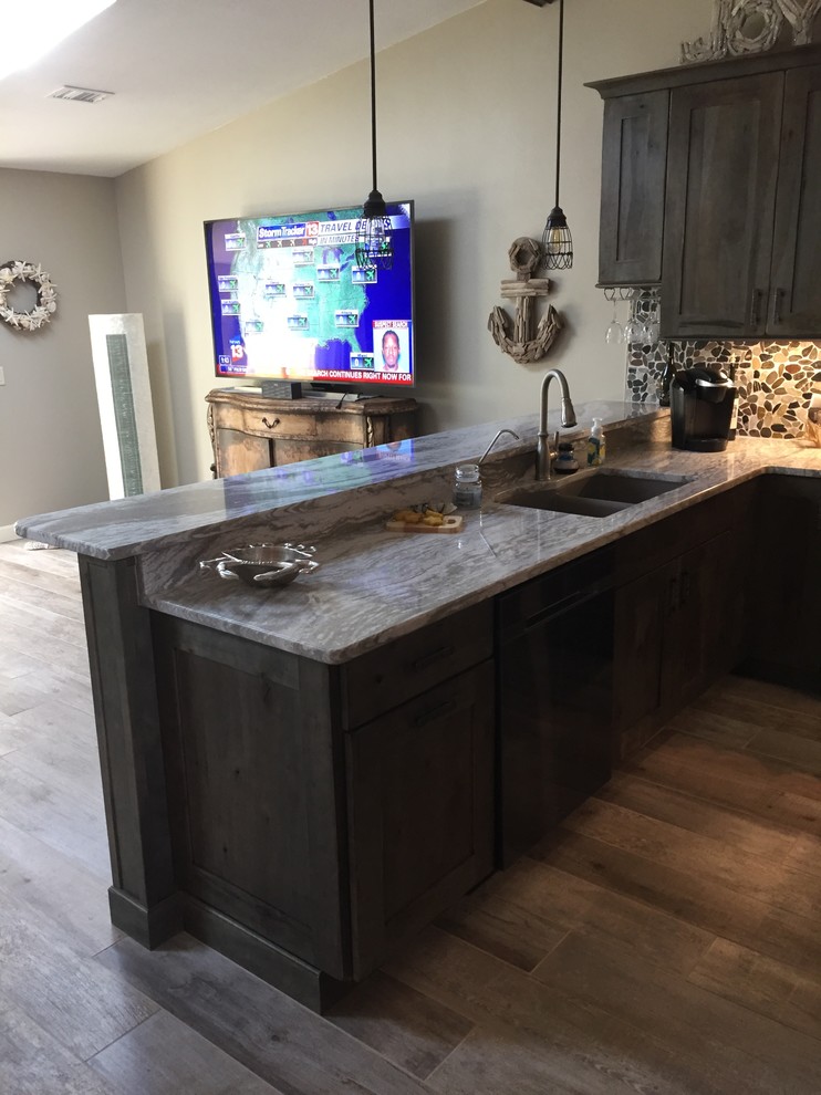 Mid-sized beach style u-shaped eat-in kitchen in Cleveland with an undermount sink, shaker cabinets, distressed cabinets, quartzite benchtops, multi-coloured splashback, stone tile splashback, black appliances, porcelain floors and a peninsula.