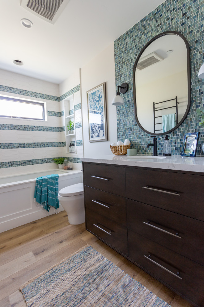 Tub/shower combo - mid-sized coastal kids' white tile vinyl floor, brown floor and single-sink tub/shower combo idea in Santa Barbara with quartz countertops, white countertops, a built-in vanity, flat-panel cabinets, brown cabinets, an undermount tub, a one-piece toilet, white walls, an undermount sink and a niche