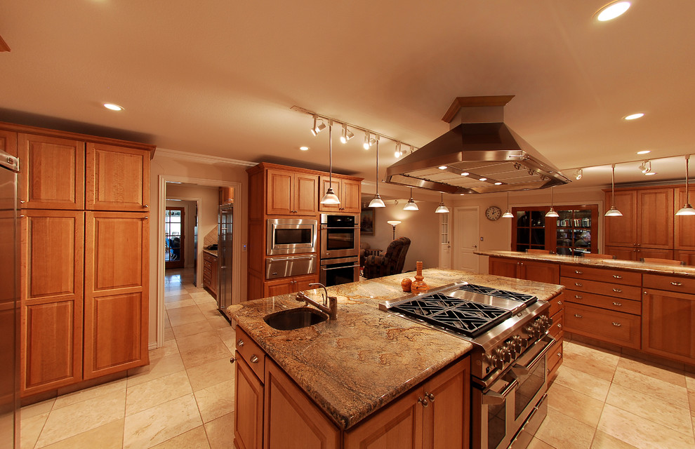 This is an example of an expansive traditional u-shaped eat-in kitchen in Chicago with raised-panel cabinets, medium wood cabinets, an undermount sink, granite benchtops, beige splashback, stainless steel appliances, ceramic floors and with island.