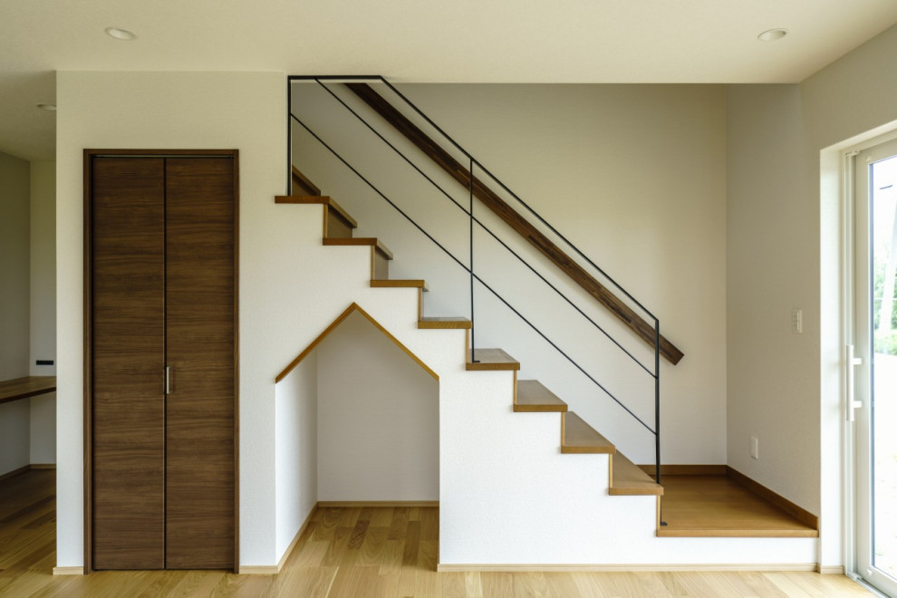 Идея дизайна: прямая деревянная лестница среднего размера в стиле модернизм с деревянными ступенями, металлическими перилами, обоями на стенах и кладовкой или шкафом под ней
