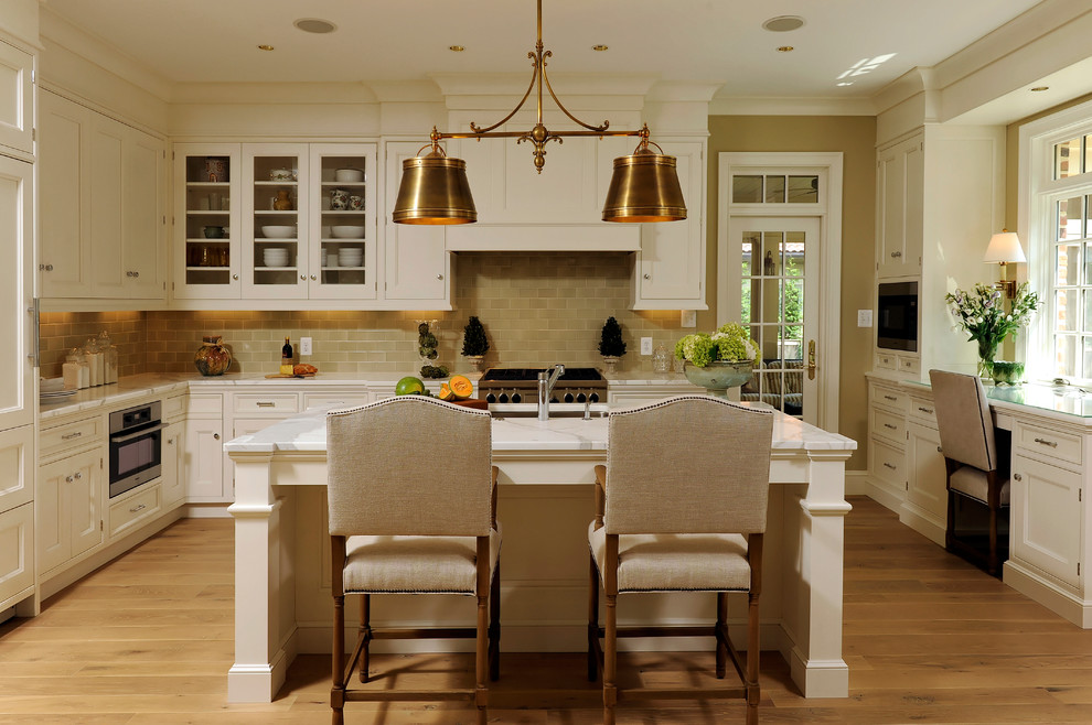 Inspiration for a mid-sized timeless l-shaped light wood floor eat-in kitchen remodel in DC Metro with shaker cabinets, white cabinets, marble countertops, beige backsplash, subway tile backsplash, stainless steel appliances, an island and an undermount sink