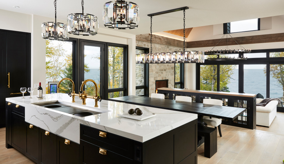 Transitional open plan kitchen in Minneapolis with a double-bowl sink, shaker cabinets, black cabinets, light hardwood floors, with island, beige floor and white benchtop.