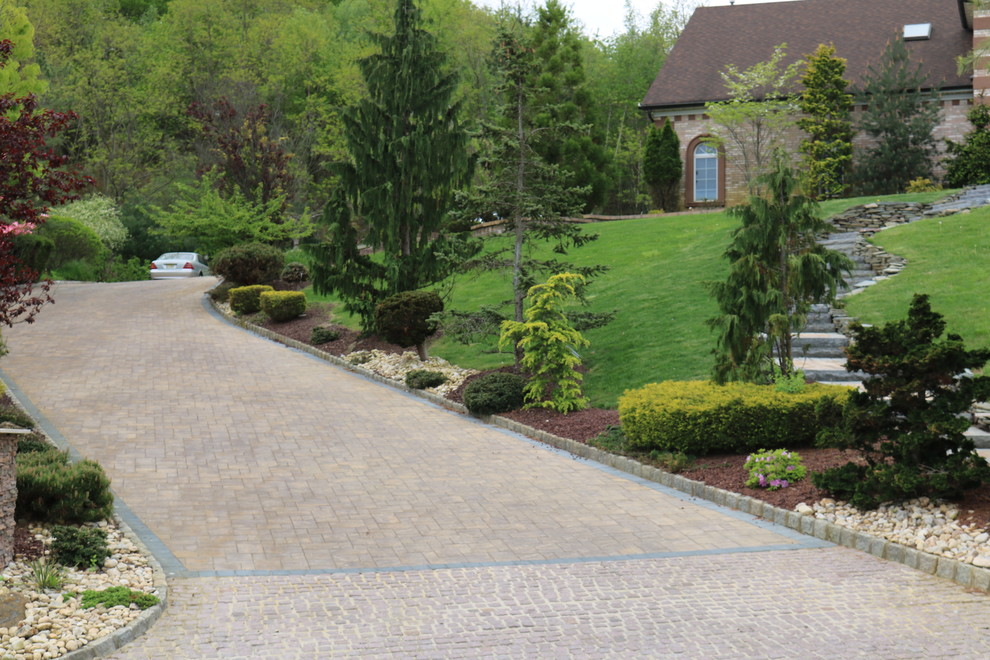 This is an example of a large modern front yard garden in New York with brick pavers.