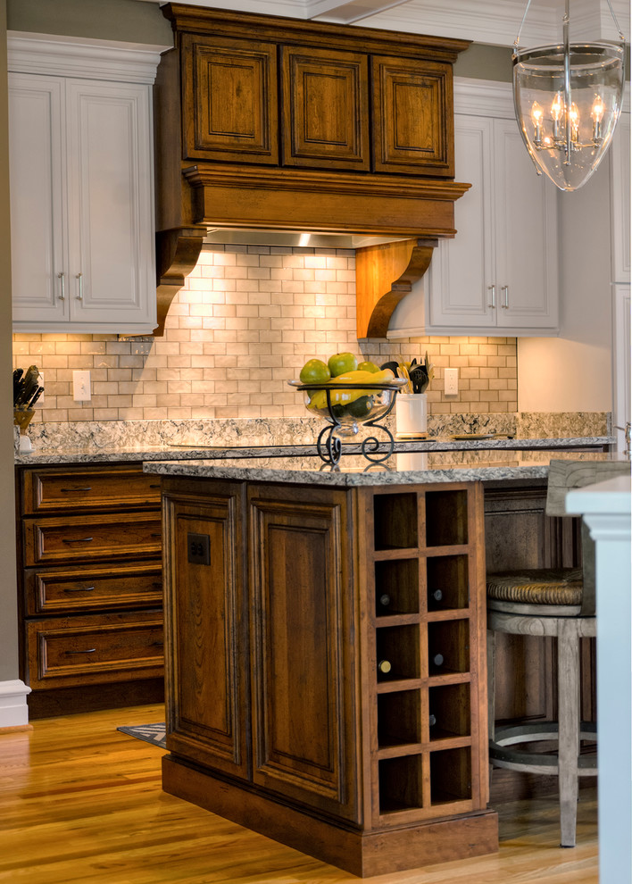 This is an example of a traditional l-shaped kitchen in DC Metro with with island, raised-panel cabinets, quartz benchtops, grey splashback and light hardwood floors.
