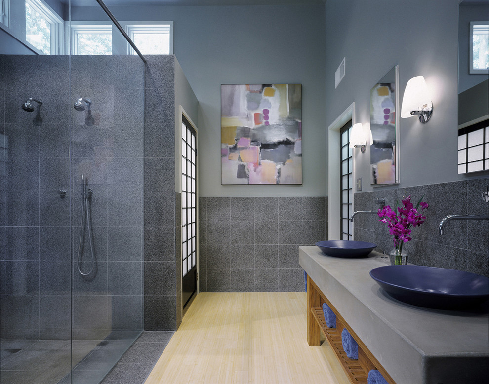 This is an example of a contemporary bathroom in DC Metro with a vessel sink, open cabinets, concrete benchtops, a double shower, gray tile and light hardwood floors.