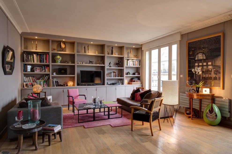 Design ideas for a mid-sized eclectic open concept family room in Paris with a library, grey walls, light hardwood floors, no fireplace and a built-in media wall.