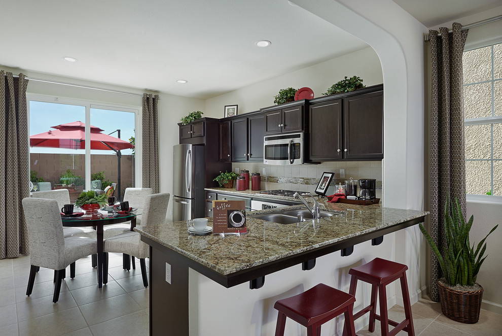 Example of a beige floor kitchen design with dark wood cabinets, granite countertops and beige backsplash