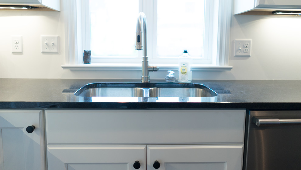 Open concept kitchen - mid-sized transitional l-shaped dark wood floor open concept kitchen idea with an undermount sink, shaker cabinets, white cabinets, granite countertops, gray backsplash, stainless steel appliances and an island