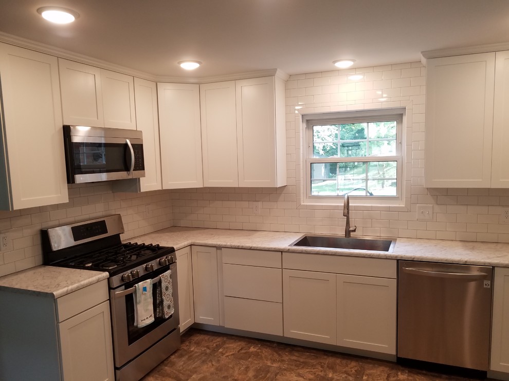 Mid-sized transitional l-shaped vinyl floor and beige floor eat-in kitchen photo in Cincinnati with a single-bowl sink, shaker cabinets, white cabinets, laminate countertops, white backsplash, porcelain backsplash, stainless steel appliances and no island