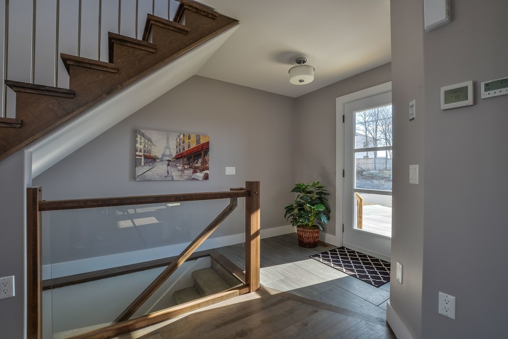 Transitional medium tone wood floor and brown floor front door photo with gray walls and a white front door