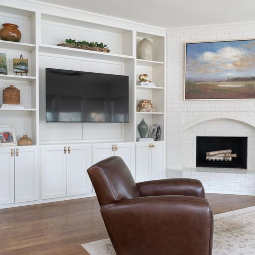 Diseño de sala de estar abierta clásica renovada grande con paredes blancas, suelo de madera clara, marco de chimenea de ladrillo, pared multimedia y suelo multicolor