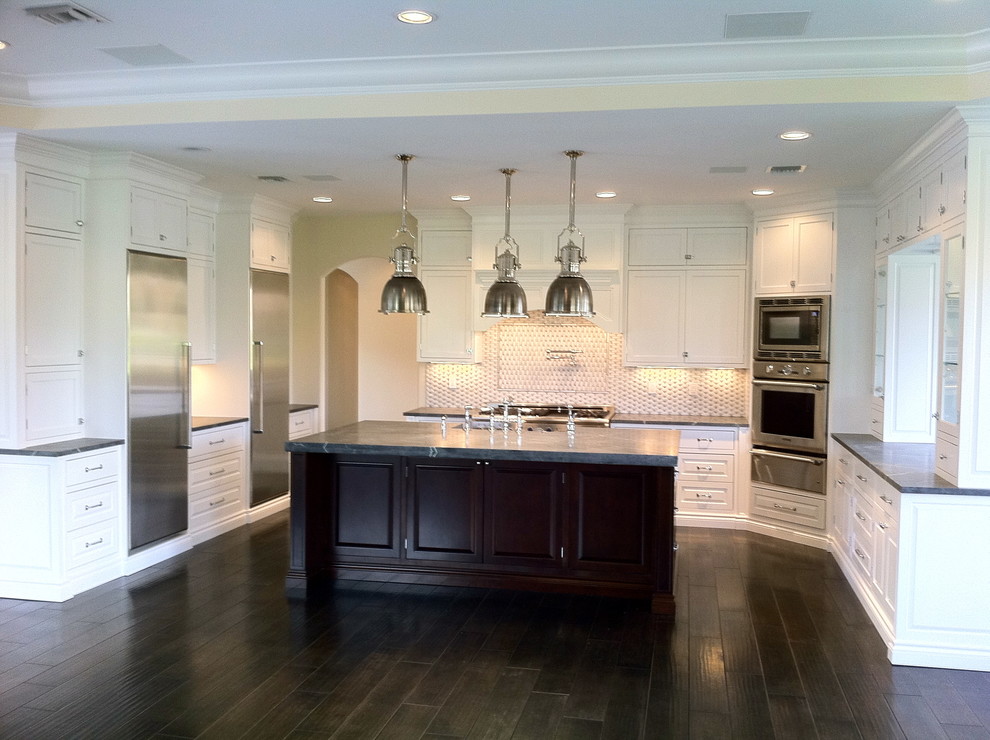 Inspiration for a large transitional u-shaped dark wood floor and brown floor open concept kitchen remodel in Miami with a farmhouse sink, shaker cabinets, white cabinets, granite countertops, multicolored backsplash, stone tile backsplash, stainless steel appliances and an island