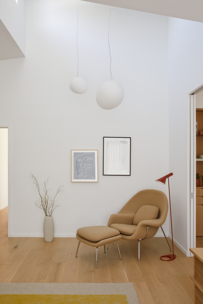 Esempio di un soggiorno moderno di medie dimensioni e chiuso con sala giochi, pareti bianche, parquet chiaro, TV a parete, pavimento marrone e soffitto a volta