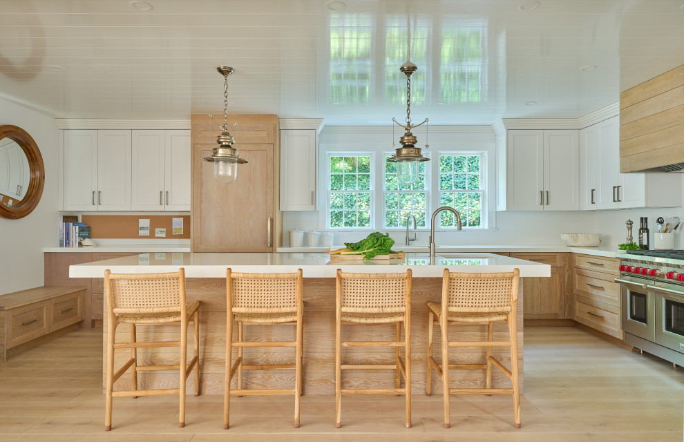 This is an example of a beach style u-shaped eat-in kitchen in New York with an undermount sink, recessed-panel cabinets, light wood cabinets, quartz benchtops, white splashback, ceramic splashback, panelled appliances, light hardwood floors, with island, white benchtop, beige floor and timber.