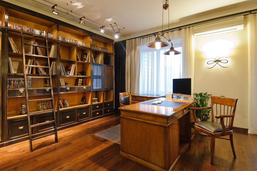 This is an example of a traditional study room in Novosibirsk with a freestanding desk, white walls and medium hardwood floors.