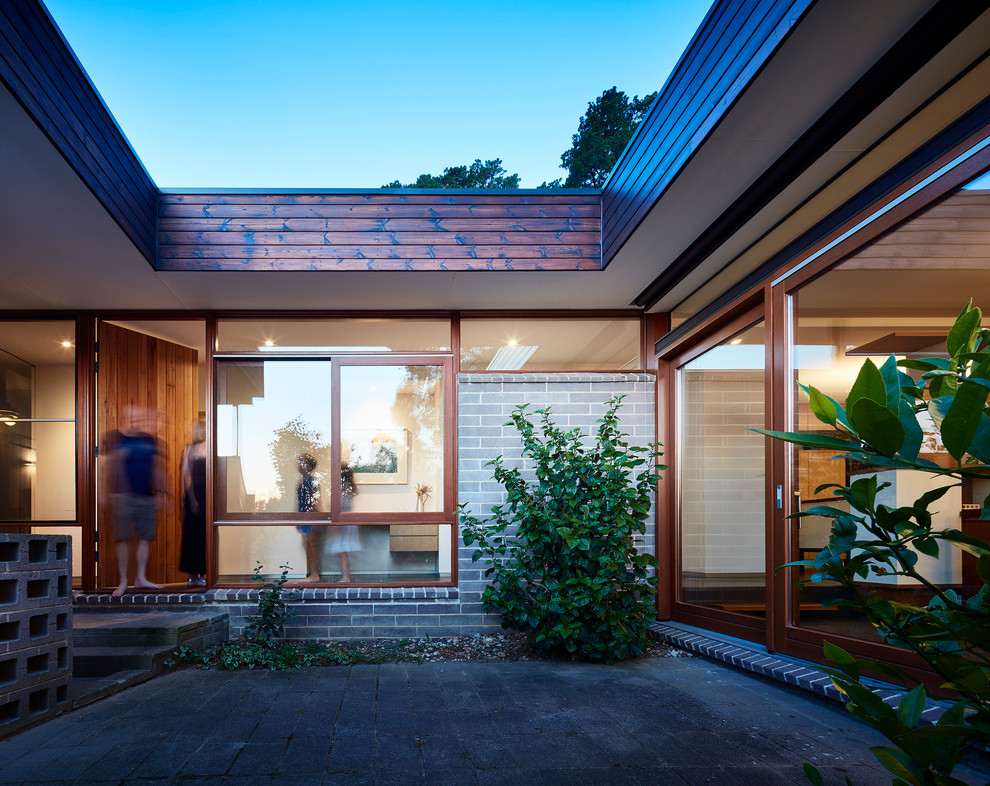 This is an example of a midcentury courtyard patio in Melbourne with concrete pavers.