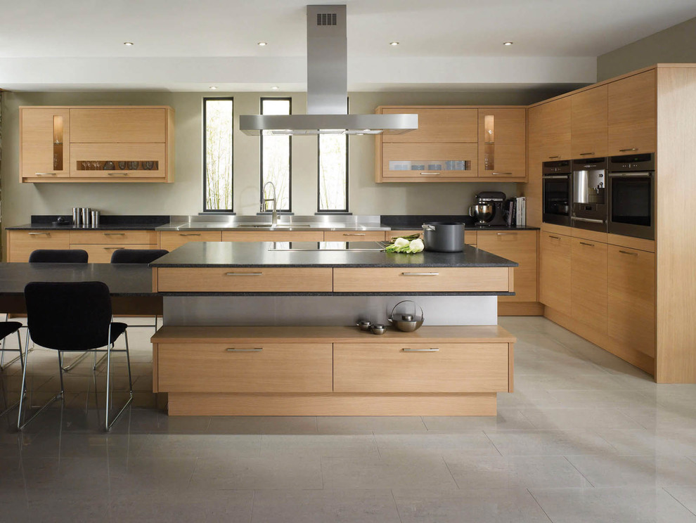 Inspiration for a contemporary l-shaped eat-in kitchen in Los Angeles with an undermount sink, flat-panel cabinets, light wood cabinets, grey splashback, stainless steel appliances, with island, grey floor and black benchtop.