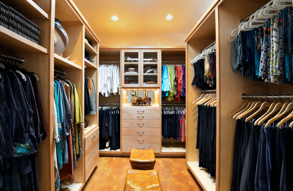 This is an example of a large transitional gender-neutral walk-in wardrobe in Dallas with flat-panel cabinets, light wood cabinets and concrete floors.