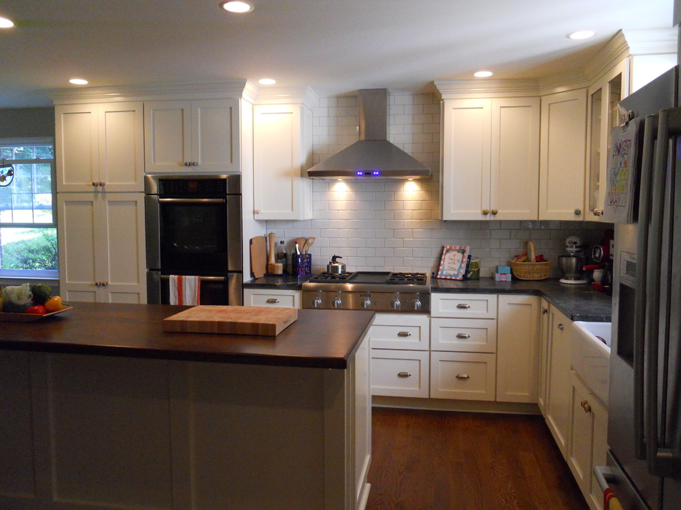 Example of a country u-shaped eat-in kitchen design in Philadelphia with a farmhouse sink, shaker cabinets, white cabinets, soapstone countertops, white backsplash, subway tile backsplash and stainless steel appliances