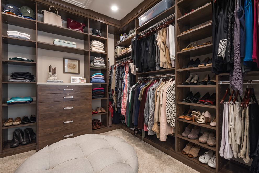 Design ideas for a large traditional gender-neutral walk-in wardrobe in Chicago with open cabinets, dark wood cabinets, carpet and beige floor.