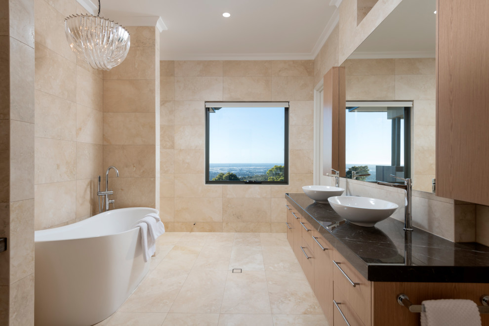 Expansive contemporary master bathroom in Perth with recessed-panel cabinets, light wood cabinets, a freestanding tub, a double shower, beige tile, travertine, beige walls, travertine floors, a vessel sink, engineered quartz benchtops, beige floor and brown benchtops.