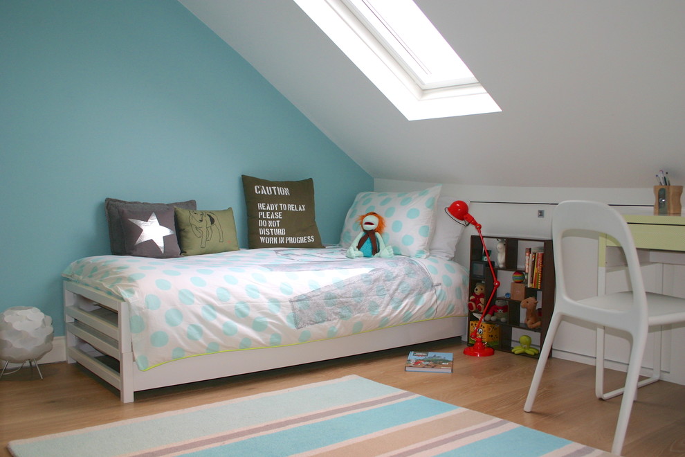 This is an example of a traditional gender-neutral kids' bedroom for kids 4-10 years old in London with blue walls and light hardwood floors.