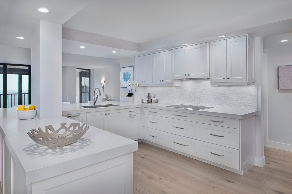 Inspiration for a mid-sized transitional u-shaped light wood floor open concept kitchen remodel in Miami with an undermount sink, shaker cabinets, white cabinets, quartz countertops, white backsplash, matchstick tile backsplash and a peninsula