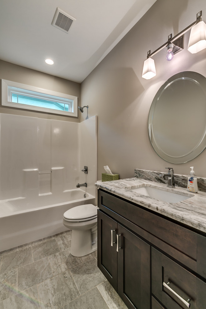 Example of a mid-sized transitional 3/4 porcelain tile and gray floor alcove bathtub design with shaker cabinets, dark wood cabinets, a two-piece toilet, brown walls, an undermount sink, granite countertops and gray countertops