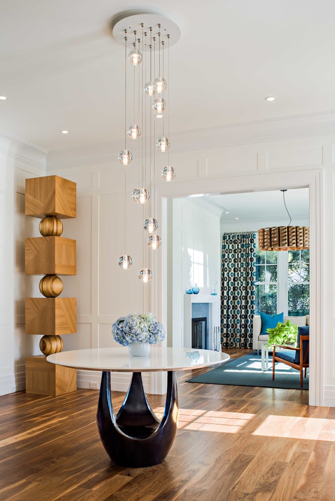 This is an example of a mid-sized contemporary foyer in New York with white walls and medium hardwood floors.