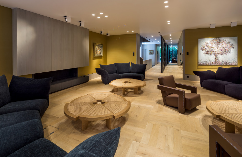 Foto di un grande soggiorno moderno aperto con angolo bar, pareti verdi, parquet chiaro, camino classico e cornice del camino in legno