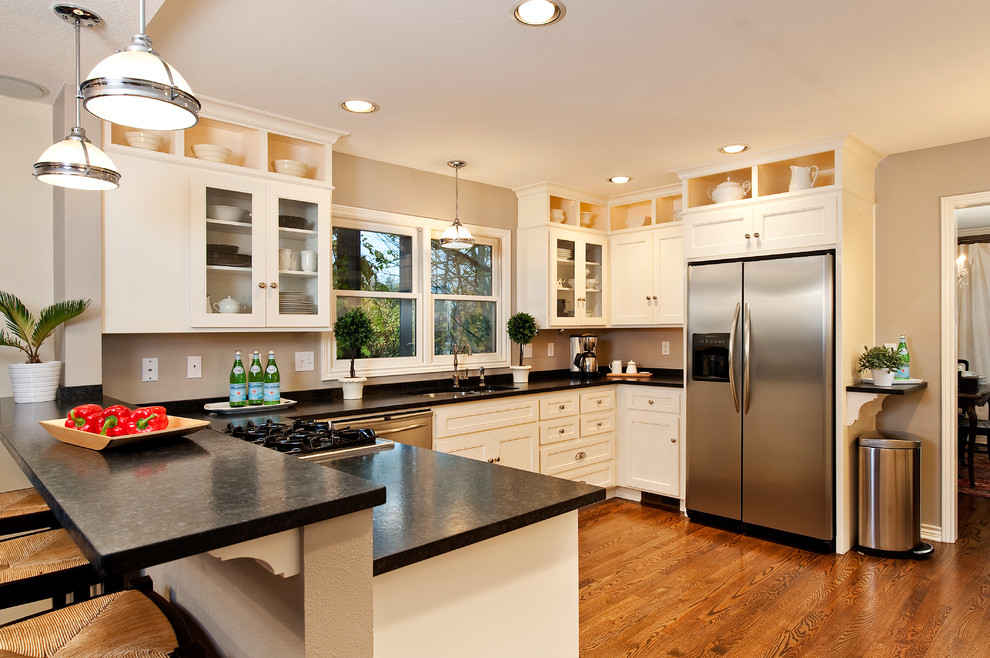 Traditional u-shaped kitchen in Portland with stainless steel appliances, white cabinets, granite benchtops, medium hardwood floors, an undermount sink and recessed-panel cabinets.
