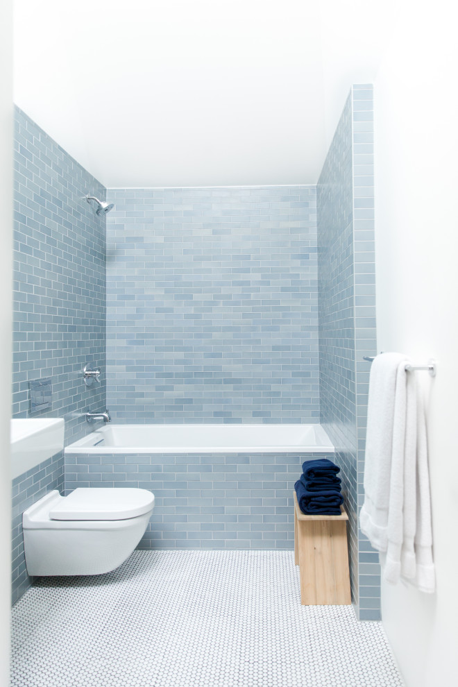 Design ideas for a mid-sized contemporary kids bathroom in Calgary with a drop-in tub, a shower/bathtub combo, a wall-mount toilet, blue tile, ceramic tile, white walls and mosaic tile floors.